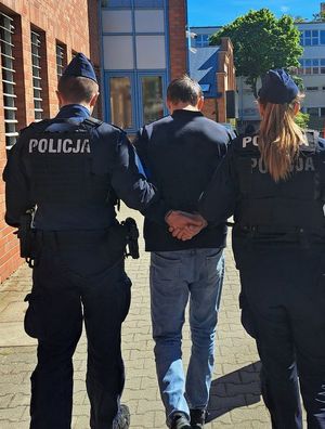 Na zdjęciu policjantka, policjant i zatrzymany mężczyzna, który ma kajdanki założone na ręce trzymane z tyłu