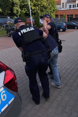 Na zdjęciu dwóch policjantów i zatrzymany mężczyzna