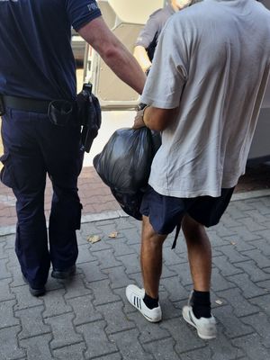 Na zdjęciu dwóch policjantów i zatrzymany mężczyzna