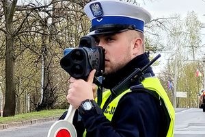 Na zdjęciu policjant ruchu drogowego, który trzyma urządzenie do pomiaru prędkości pojazdów