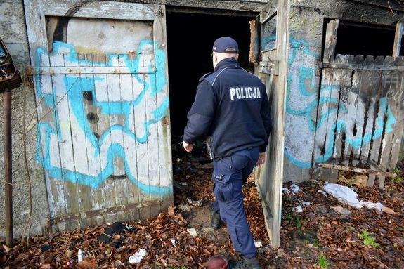 Na zdjęciu policjant, który wchodzi do pustostanu