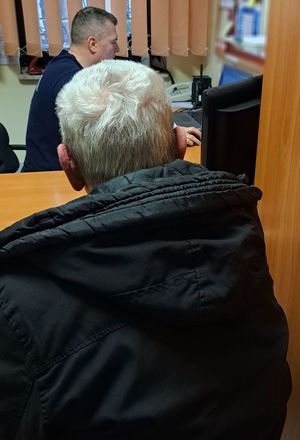 Na zdjęciu zatrzymany mężczyzna, a w tle policjant siedzący przy biurku