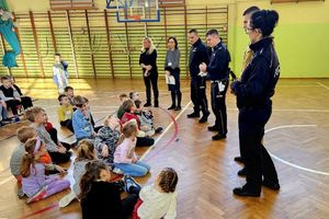 Na zdjęciu troje policjantów, strażak, dwie kobiety w strojach cywilnych i grupa dzieci