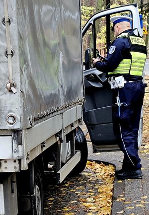 Na zdjęciu policjant stojący przy samochodzie